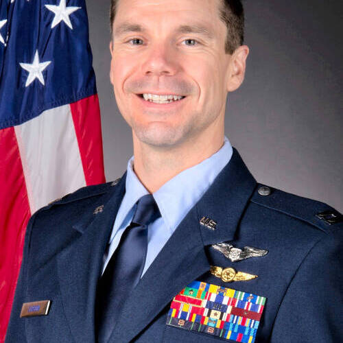 Zach Carson wearing his full dress uniform with an American flag behind his shoulder